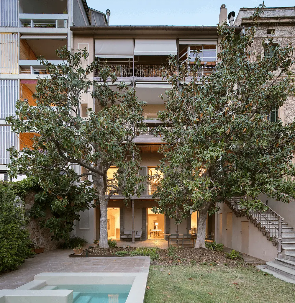 Courtyard with trees and a pool in front of a historical building